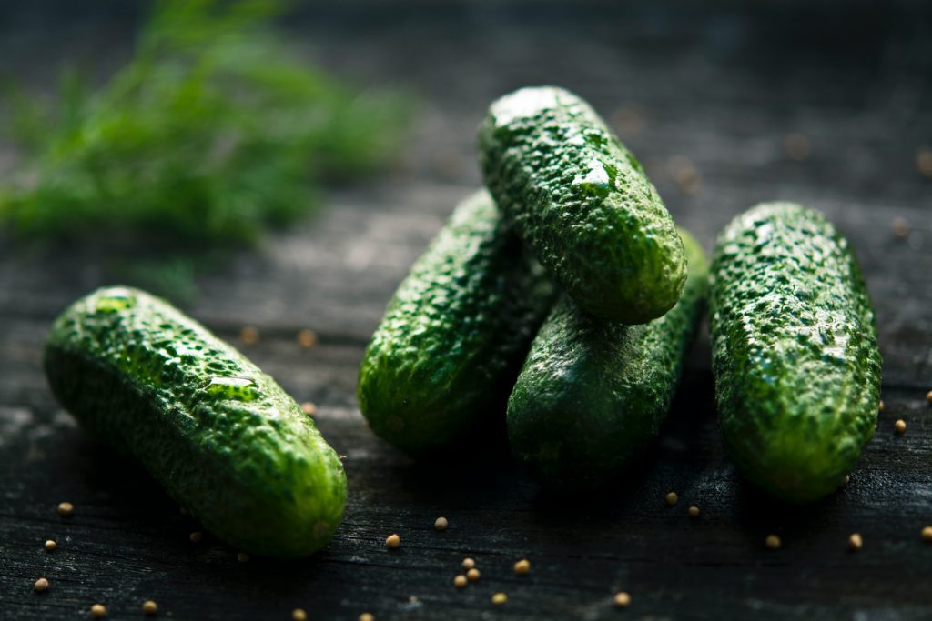 3 green cucumbers on black wooden table